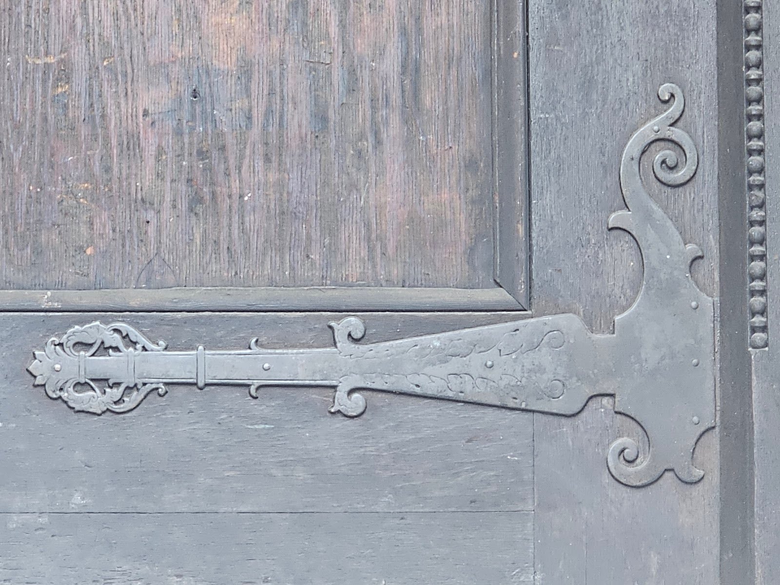 Black iron strap hinges on masonry wall