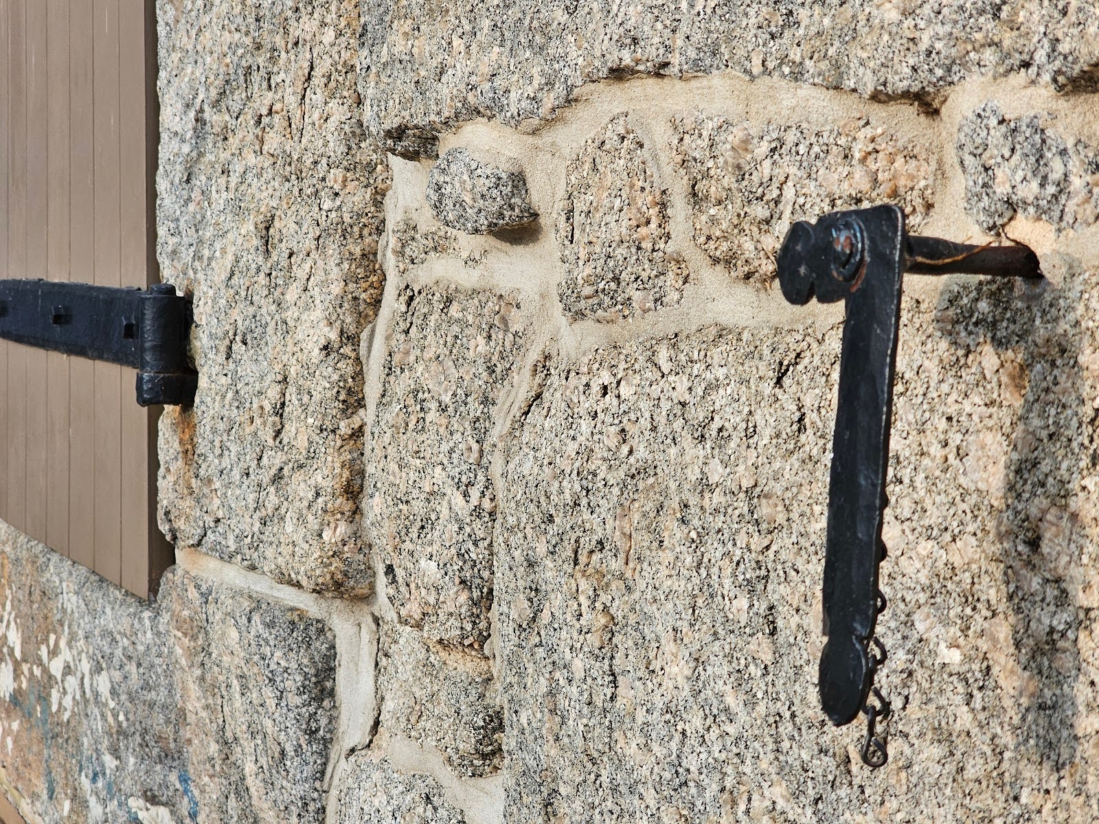 Close-up of metal door dog on historic masonry surface