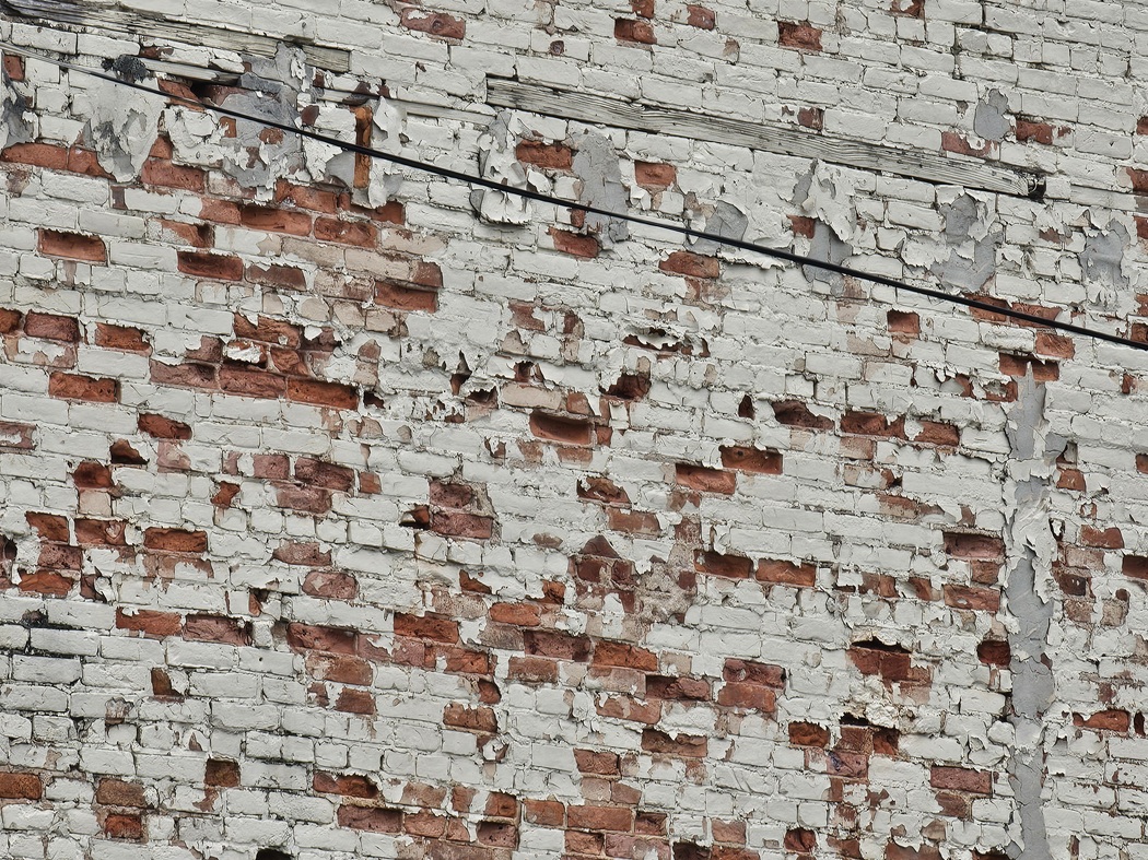 Masonry specialist in Washington DC repairing severe brick spalling on a historic building wall