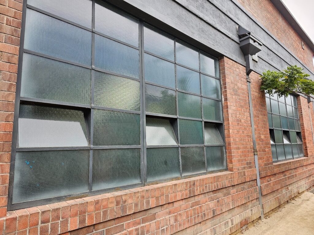 Close-up of industrial fenestration integrated into an old brick masonry façade