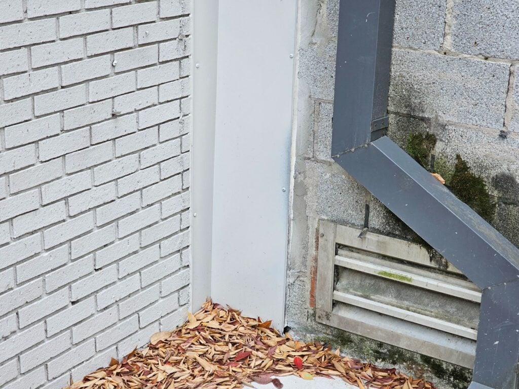 Close-up of metal flashing detail between brick veneer and concrete block wall