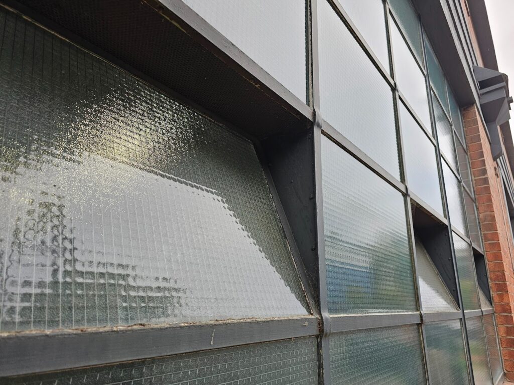 Metal-framed industrial window fitted into preserved brick wall opening