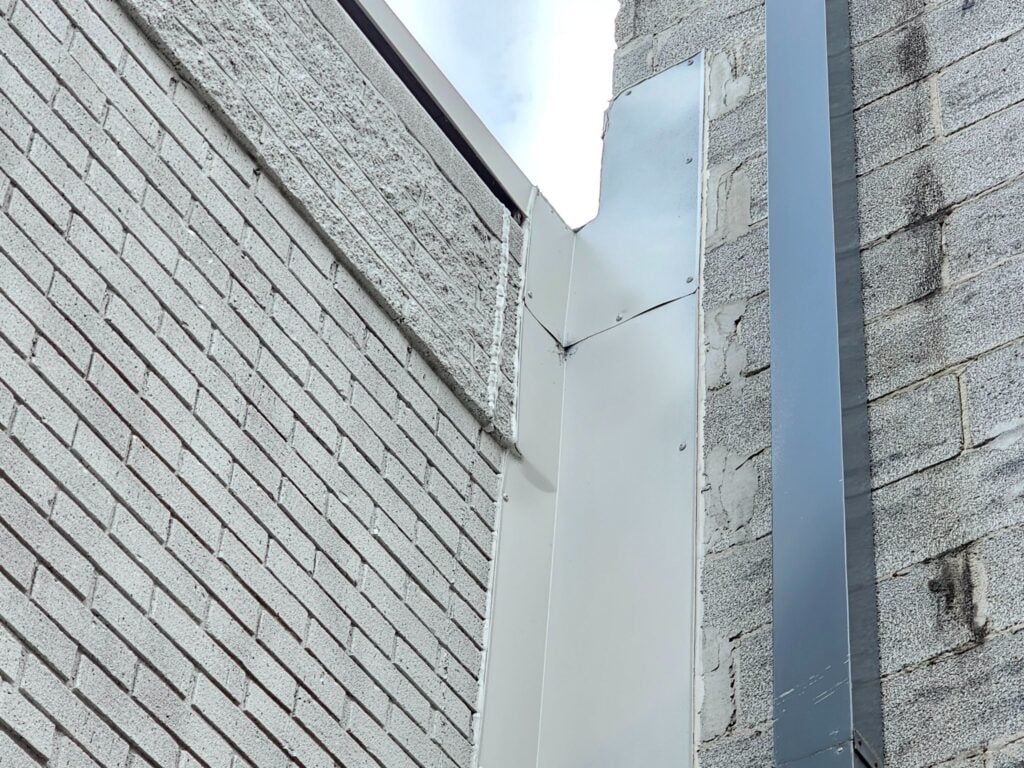 Properly installed metal flashing at a brick to block wall transition