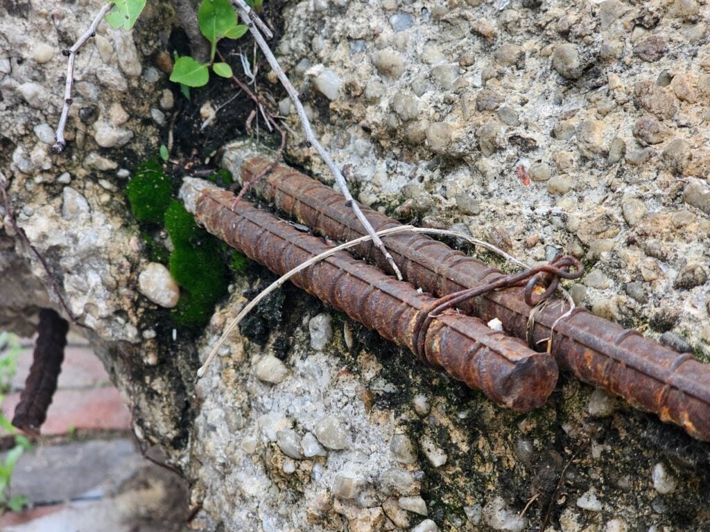 Corroded rebar visible in cracked and deteriorated concrete