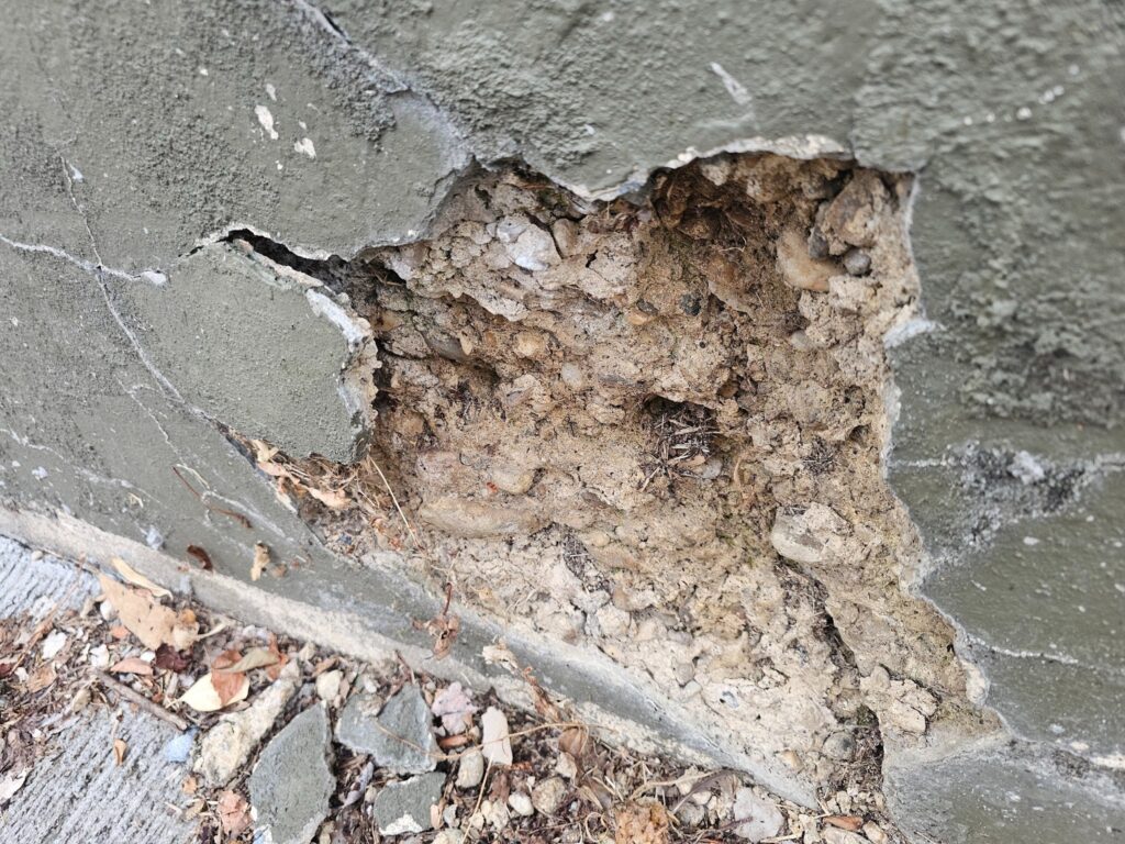 Damaged retaining wall with visible cracks and structural movement